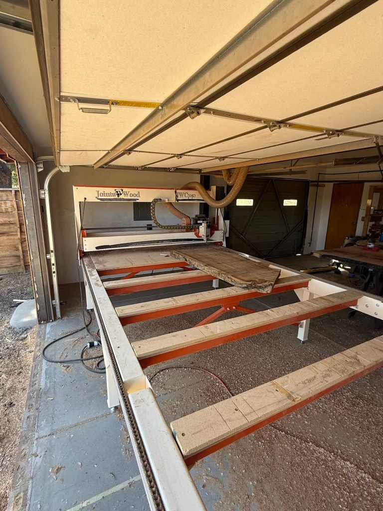 A live-edge slab on the table of the CNC router that flattens slabs