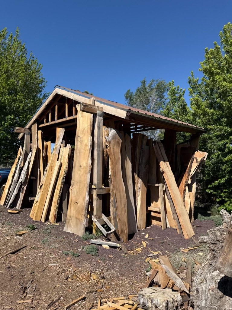 Live-edge slabs leaning against the posts of an open-sided shed